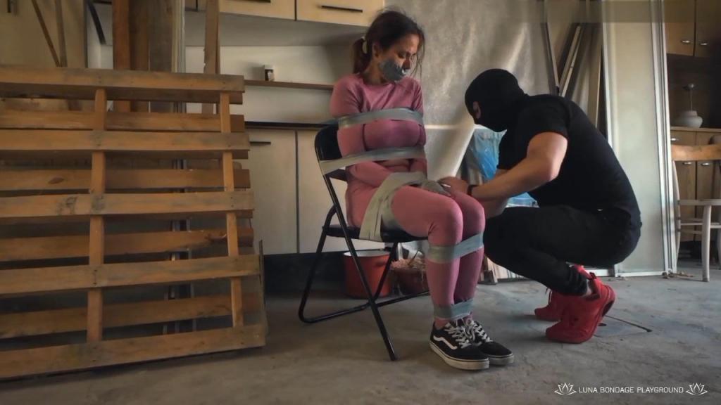 Luna and the mad stalker 2 - Trunk Capture, PVC Tape Bondage, Nude, Extreme Hogtie, Tape Gag and Bli Luna and the mad stalker 2 - Trunk Capture, PVC Tape Bondage, Nude, Extreme Hogtie, Tape Gag and Blindfold, Groping, Struggling - 1080p HD<br><br>The scene opens with a chilling reveal: Luna has been staged inside the trunk of a car, completely immobilized and silenced by multiple layers of gray PVC tape. Her wrists are bound, her body wrapped, and a thick tape gag seals her mouth.<br> and a masked figure drags her out into the dim, gritty atmosphere of a private garage. She doesn't know where she is and she doesn't know that she will be punished with a brutal hogtie.<br><br>The masked captor guides Luna to a chair, where he begins the slow, methodical process of securing her. Layer after layer of gray PVC tape is applied with precision - wrists to the armrests, ankles bound, torso wrapped tight. Luna, dressed in a soft pink sporty outfit, struggles against the restraints in panic, but the tape holds firm. Left alone on the chair, she writhes and twists, testing every wrap, only to realize she is utterly at his mercy.<br>The second act escalates the tension. The masked figure returns and, with deliberate control, begins to strip away her pink outfit,The environment - dirty, cluttered, and raw - amplifies the contrast between her helplessness and his dominance. Spotting a wooden pallet, he decides to elevate the scene. Luna is lifted and placed on the rough surface, her eyes sealed with two tight wraps of tape blindfold, plunging her into total sensory deprivation.<br><br>But the captor isn't finished. Believing the scene can reach even greater intensity, he begins the final transformation. Pulling her bound limbs together, he crafts an unforgiving, extreme tape hogtie, putting her body into a tight, arched position of absolute surrender. Luna, blindfolded, gagged, and completely immobilized on the pallet, can only breathe through the intensity of the moment, lost in a fantasy of total helplessness.<br><br><br><br><br><br>