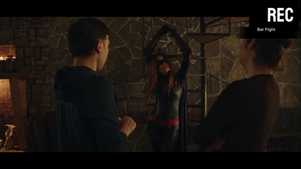 Bar Fight A superheroine is defeated by her enemy in a latex peril scenario involving hair-pulling, unmasking, de-booting, bear hugs, and rough male handling.