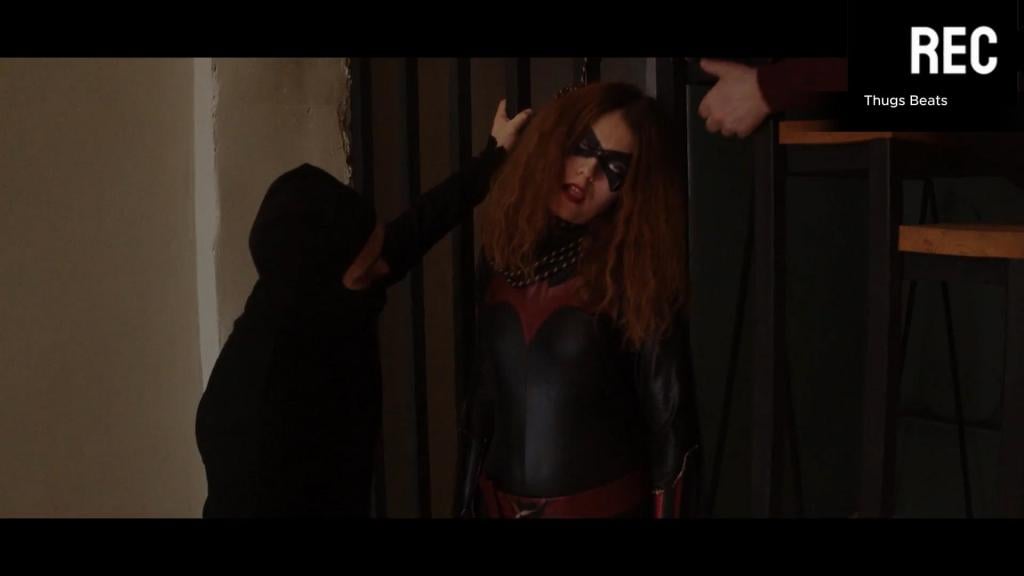Thugs Beats A superheroine is defeated by her enemy in a latex peril scenario involving hair-pulling, unmasking, de-booting, bear hugs, and rough male handling.